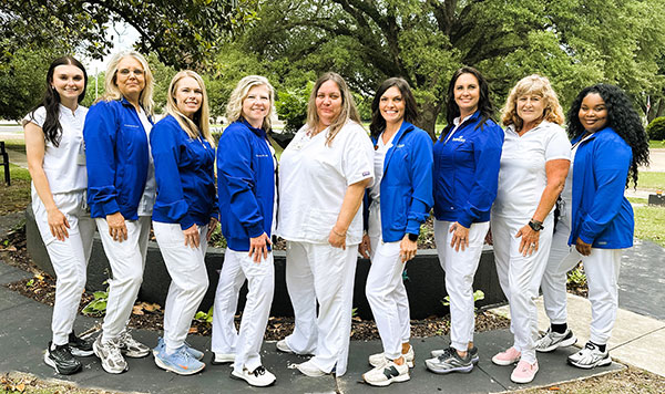 Group of women in uniforms posing outdoors.