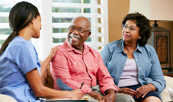 Caregiver discussing with an older couple in a home.